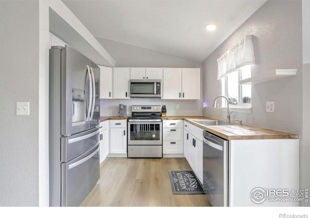 kitchen with wooden counters, white cabinetry, appliances with stainless steel finishes, and sink