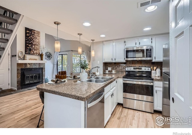 kitchen featuring white cabinetry, appliances with stainless steel finishes, a kitchen bar, and kitchen peninsula