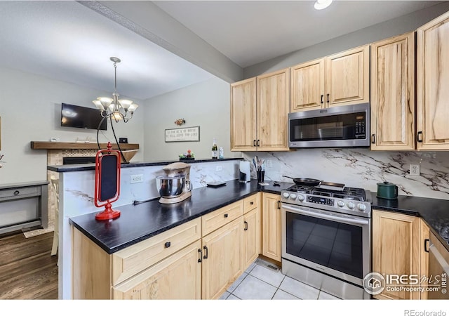 kitchen with kitchen peninsula, decorative light fixtures, light brown cabinetry, a chandelier, and appliances with stainless steel finishes