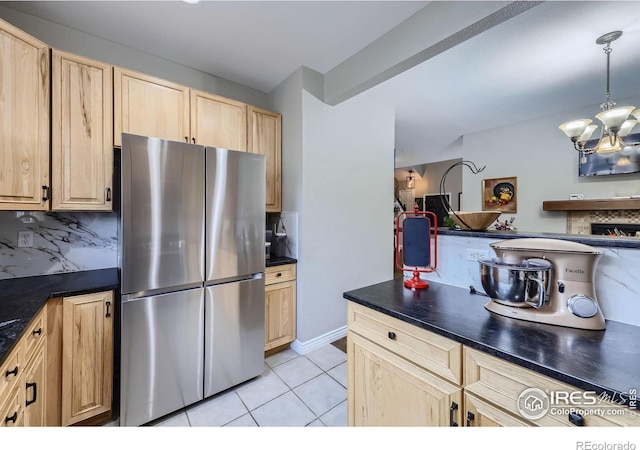 kitchen featuring decorative backsplash, decorative light fixtures, stainless steel refrigerator, light tile patterned floors, and an inviting chandelier