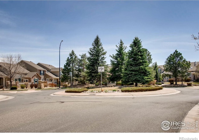 view of street with a residential view, sidewalks, street lights, traffic signs, and curbs
