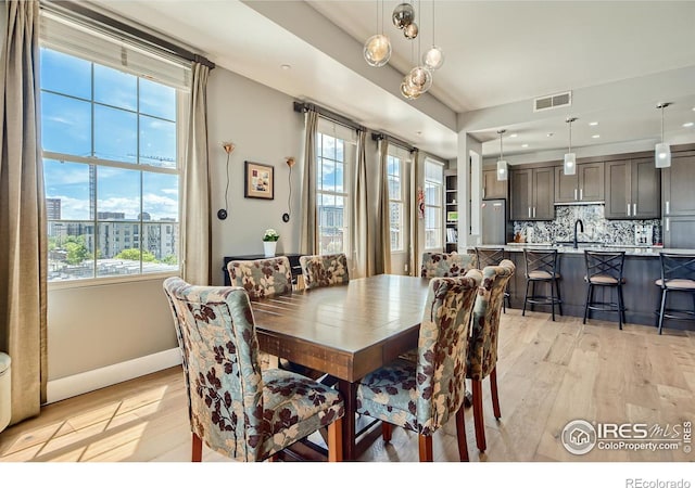 dining space with light hardwood / wood-style floors, sink, and a wealth of natural light