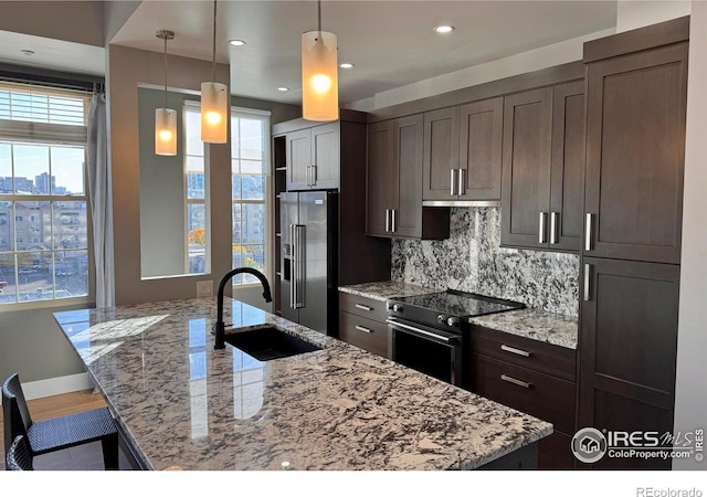 kitchen with plenty of natural light, light stone counters, appliances with stainless steel finishes, and pendant lighting