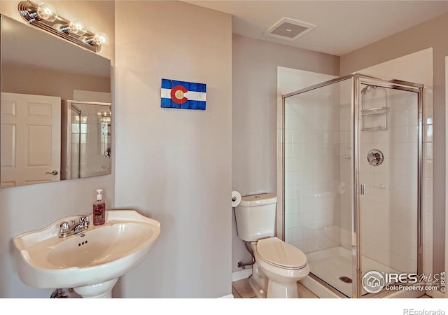 bathroom with a shower with door, sink, and toilet