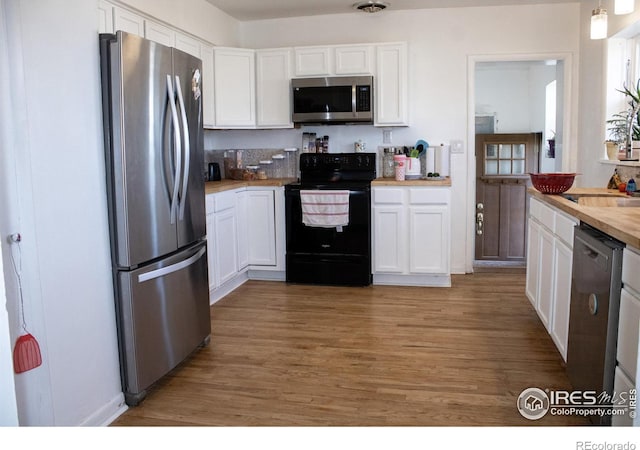 kitchen with white cabinets, appliances with stainless steel finishes, butcher block counters, dark wood-type flooring, and pendant lighting