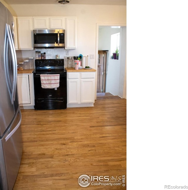 kitchen featuring appliances with stainless steel finishes, light wood-type flooring, white cabinetry, and butcher block counters