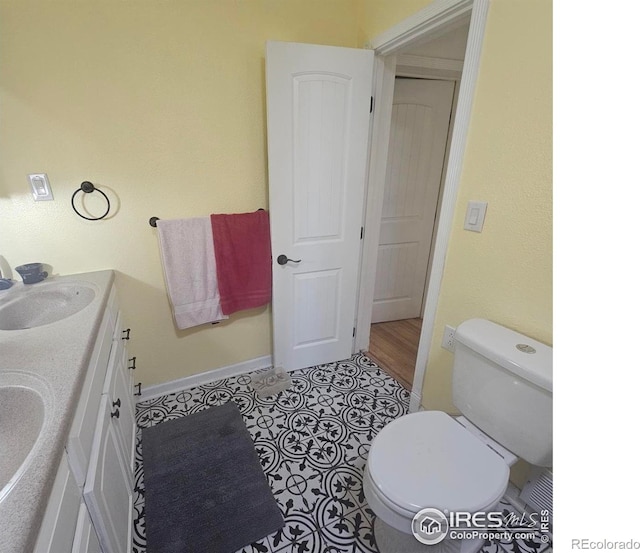 317 Second St, Roggen, CO 80652 - bathroom with a sink, double vanity, toilet, and baseboards