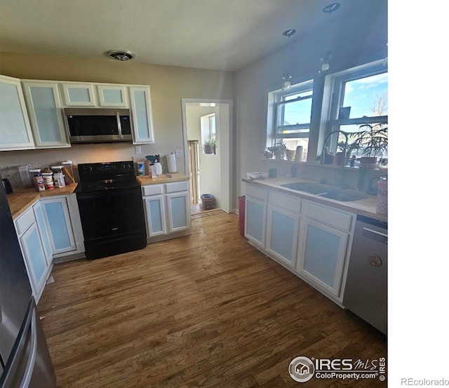 317 Second St, Roggen, CO 80652 - kitchen with white cabinets, black range with electric stovetop, stainless steel microwave, and dark wood-type flooring