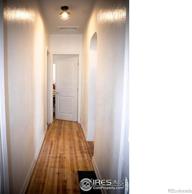 317 Second St, Roggen, CO 80652 - hall featuring arched walkways, baseboards, visible vents, and wood finished floors