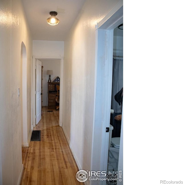 317 Second St, Roggen, CO 80652 - corridor with light wood finished floors, arched walkways, baseboards, and visible vents