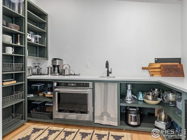 bar featuring sink, light hardwood / wood-style flooring, and oven