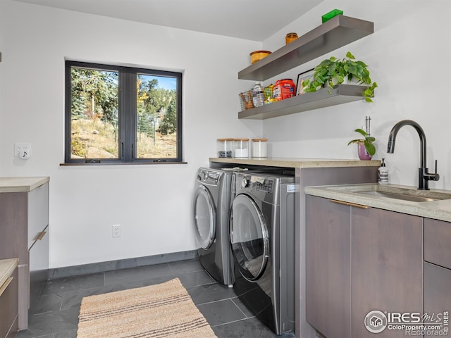 laundry area featuring independent washer and dryer, sink, and dark tile patterned flooring