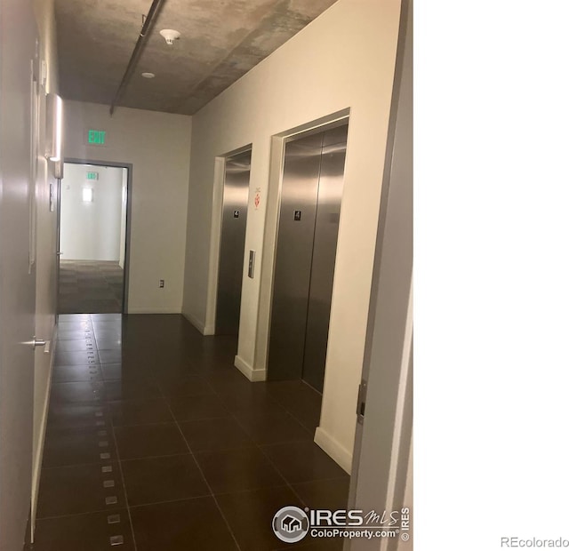 corridor with elevator and dark tile patterned floors