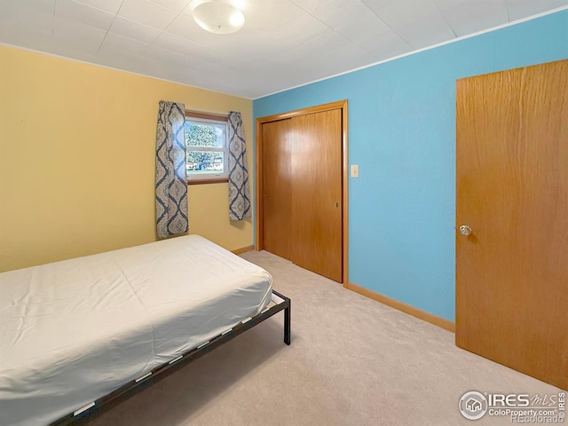 bedroom with baseboards, a closet, and carpet flooring