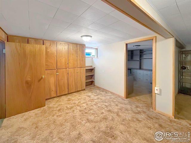 basement featuring baseboards and light colored carpet