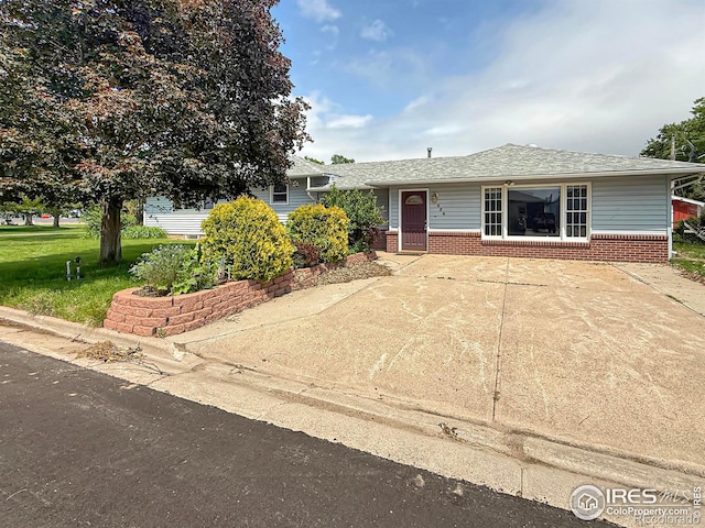 654 W Strohm St, Haxtun, CO 80731 - view of front facade with brick siding, a front yard, and a shingled roof
