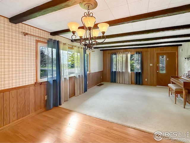 654 W Strohm St, Haxtun, CO 80731 - unfurnished dining area with wooden walls, a chandelier, beamed ceiling, and wood finished floors