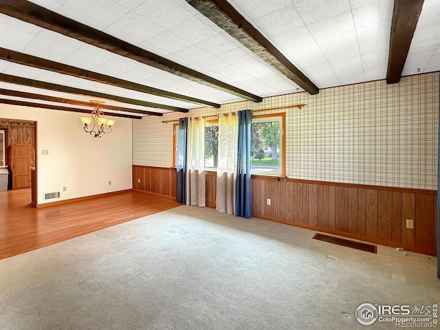 654 W Strohm St, Haxtun, CO 80731 - carpeted empty room featuring a chandelier, beam ceiling, wainscoting, wooden walls, and wood finished floors