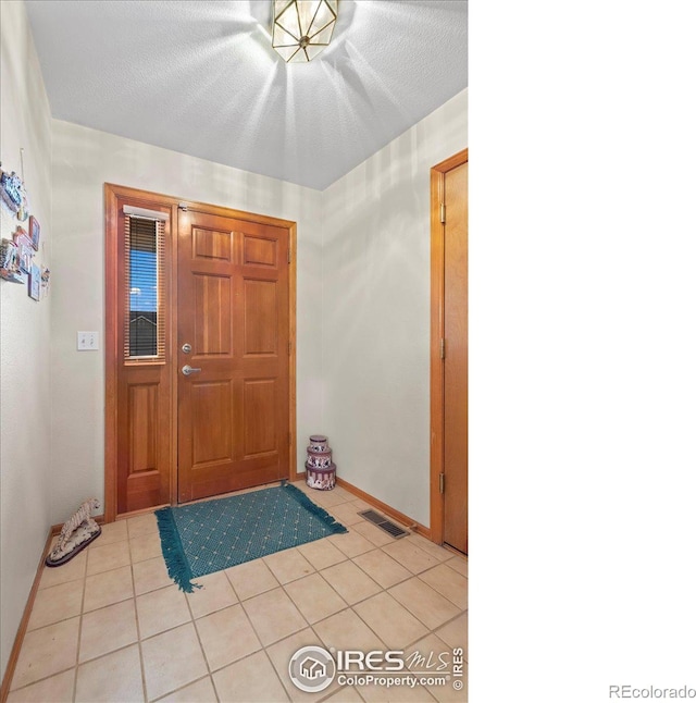 foyer entrance with light tile patterned flooring and a textured ceiling