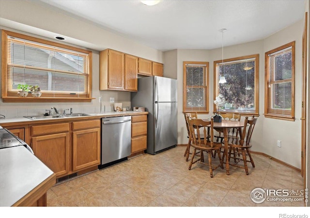 kitchen featuring stainless steel appliances, a sink, visible vents, baseboards, and light countertops