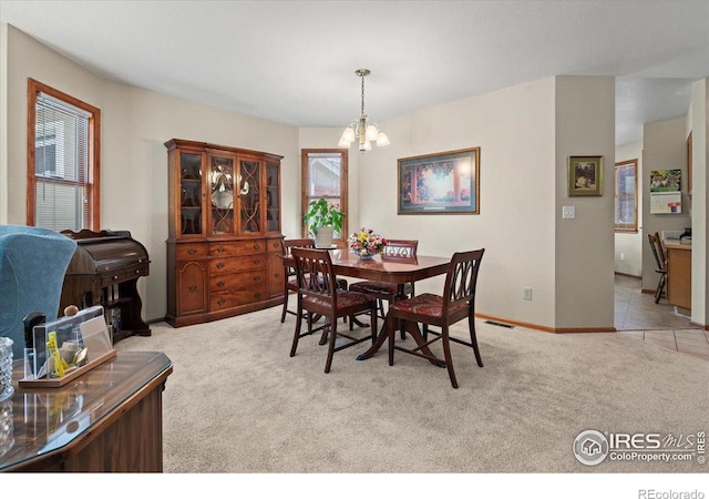 carpeted dining area featuring baseboards, visible vents, and an inviting chandelier