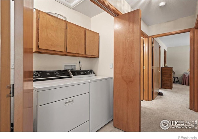 washroom with cabinet space, washing machine and dryer, and light colored carpet