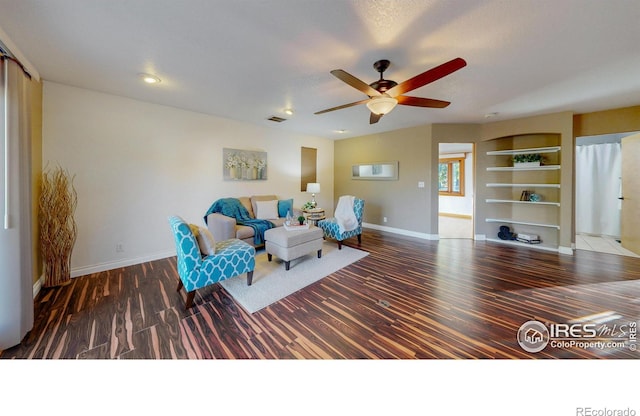 unfurnished room with built in shelves, ceiling fan, and dark hardwood / wood-style flooring