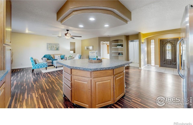 kitchen featuring a textured ceiling, dark hardwood / wood-style floors, a kitchen island, and ceiling fan