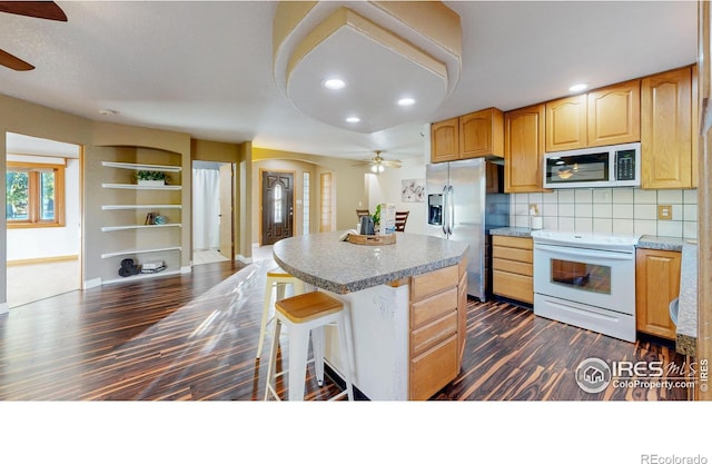 kitchen with dark hardwood / wood-style floors, tasteful backsplash, appliances with stainless steel finishes, and a center island