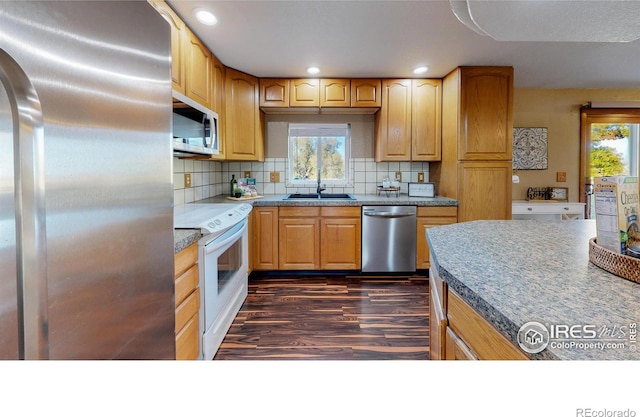 kitchen with dark wood-type flooring, tasteful backsplash, sink, and stainless steel appliances