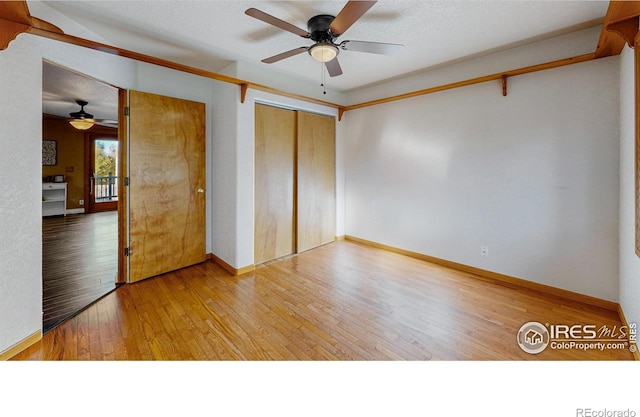 unfurnished bedroom featuring a textured ceiling, wood-type flooring, ceiling fan, and a closet