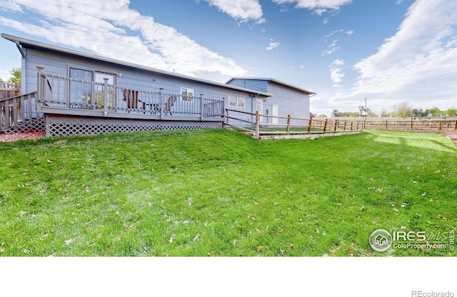 rear view of property featuring a wooden deck and a yard