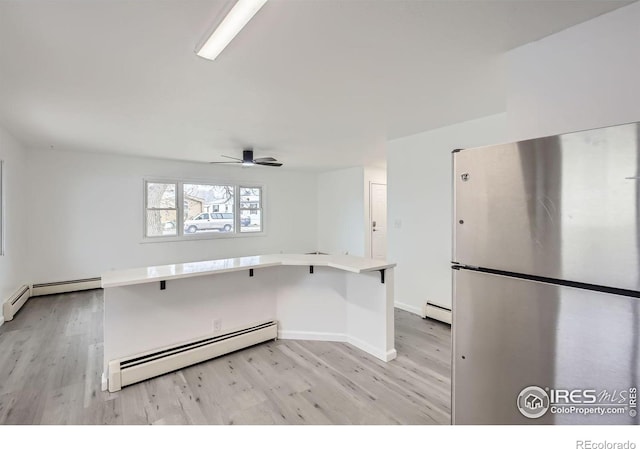 kitchen featuring stainless steel refrigerator, ceiling fan, and a baseboard heating unit