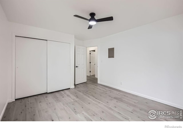 unfurnished bedroom featuring light hardwood / wood-style floors, a closet, ceiling fan, and electric panel