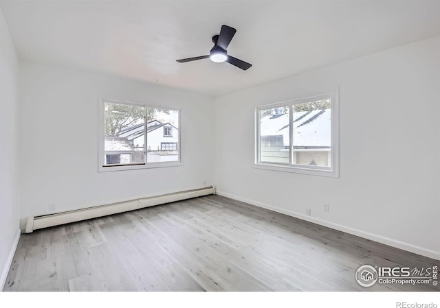 spare room with ceiling fan, light wood-type flooring, and baseboard heating