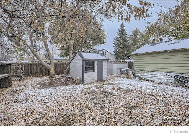 yard layered in snow featuring a storage unit