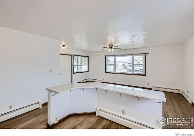 kitchen featuring dark wood-type flooring, a breakfast bar area, and a baseboard radiator