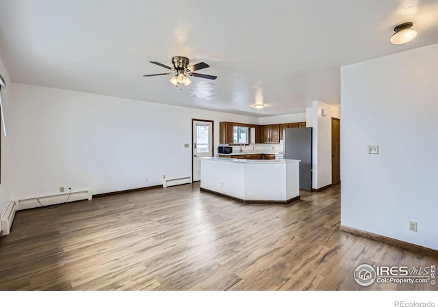 kitchen with stainless steel fridge, light wood-type flooring, a baseboard radiator, and ceiling fan