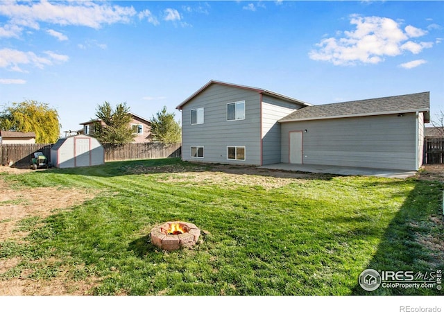 back of house featuring a patio, a lawn, a fire pit, and a storage unit