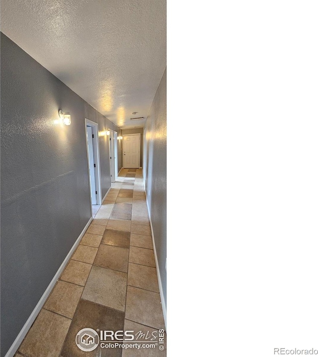 18542 County Road 8, Wiggins, CO 80654 - corridor featuring a textured ceiling, baseboards, and light tile patterned floors