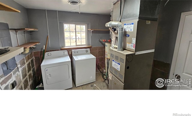 18542 County Road 8, Wiggins, CO 80654 - laundry room with washing machine and dryer, heating unit, water heater, and a wainscoted wall