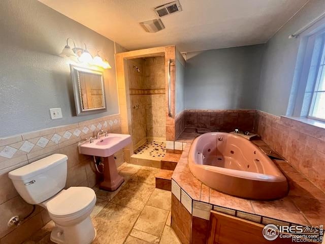 18542 County Road 8, Wiggins, CO 80654 - full bathroom featuring a shower stall, toilet, a tub with jets, and tile walls
