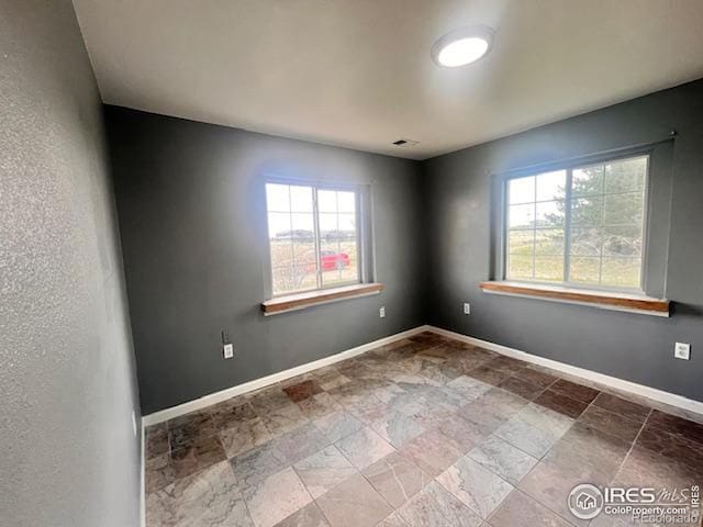 18542 County Road 8, Wiggins, CO 80654 - empty room with healthy amount of natural light, stone finish floors, and baseboards