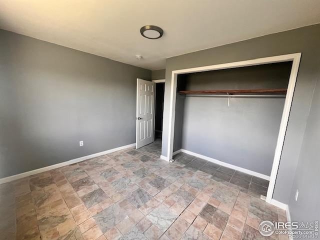 18542 County Road 8, Wiggins, CO 80654 - unfurnished bedroom featuring stone finish flooring and baseboards