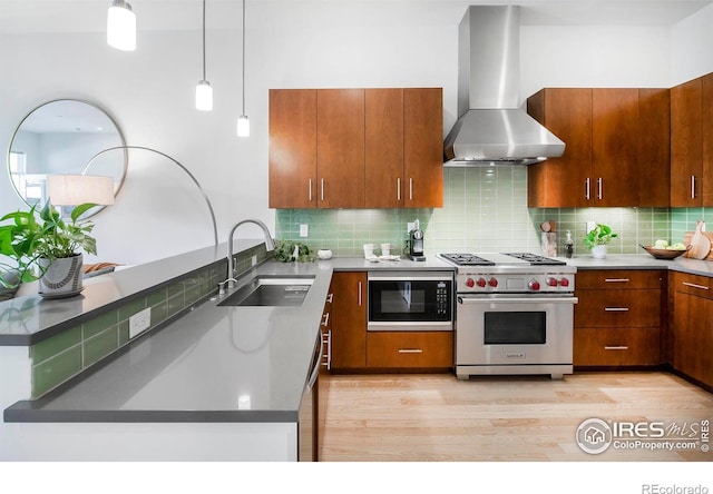 kitchen with wall chimney exhaust hood, sink, premium stove, built in microwave, and light wood-type flooring