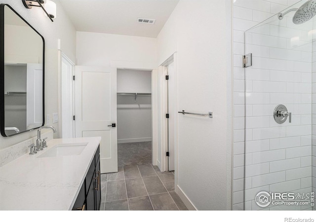 bathroom featuring tile patterned flooring, vanity, and a tile shower