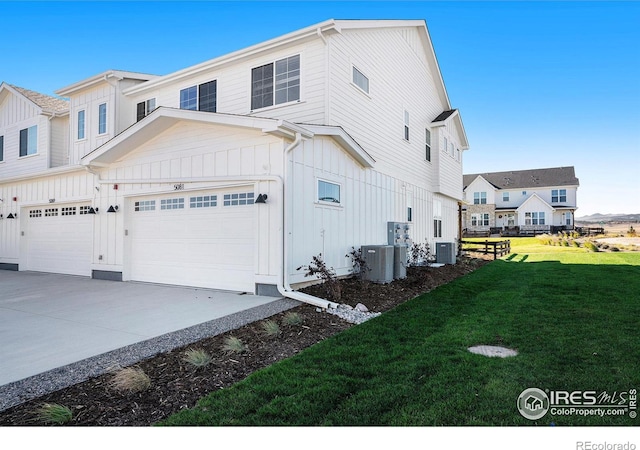 view of side of property with a garage, cooling unit, and a yard