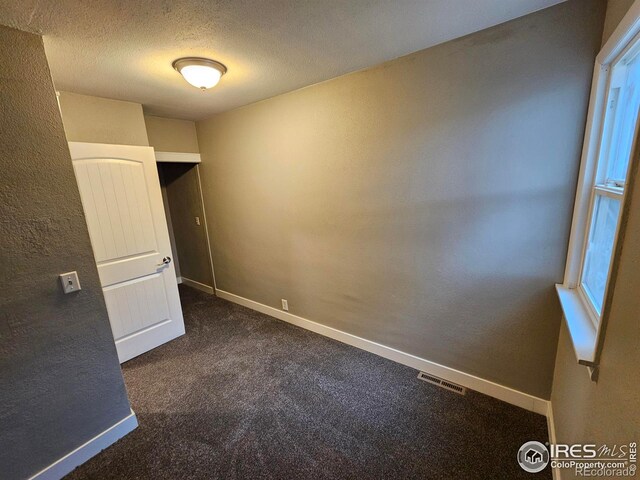 carpeted spare room with a textured ceiling