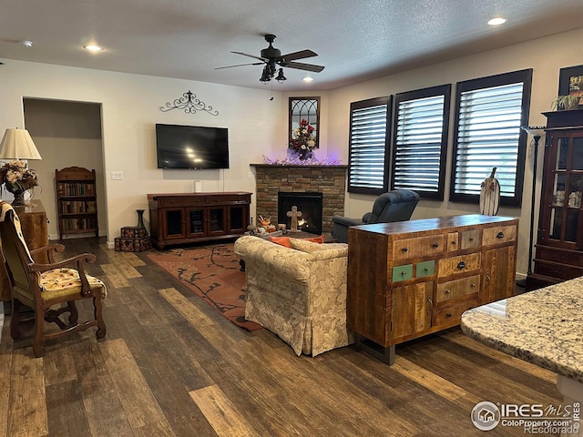 living room featuring a textured ceiling, dark hardwood / wood-style floors, ceiling fan, and a fireplace