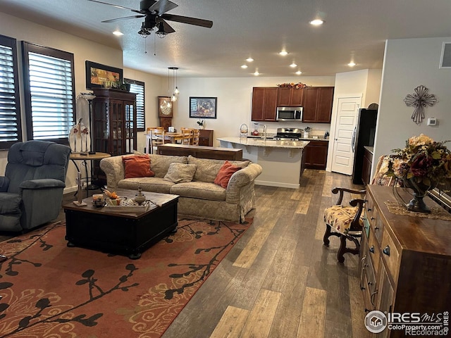 living room featuring ceiling fan and dark wood-type flooring